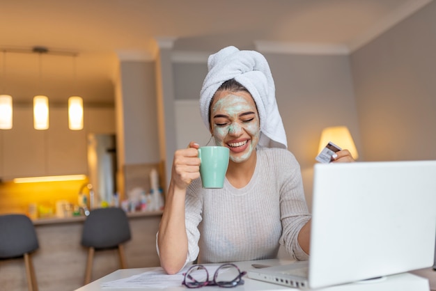 Woman wearing facial mask enjoying at home and using her laptop.