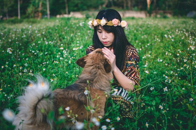 Woman wearing flowers while sitting with dog on field