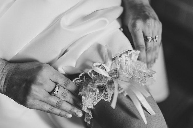 Woman wearing a garter on the leg. The bride holds in hand