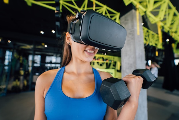 Woman wearing glasses of the virtual reality exercising with\
dumbbells