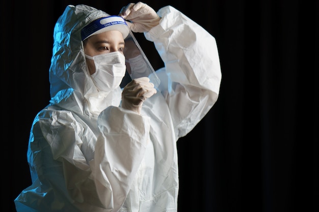 Woman wearing gloves, biohazard protective suit, face shield and mask. For corona virus or Covid-19 protection.