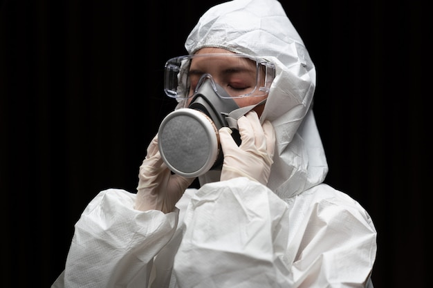Donna che indossa guanti con tuta e maschera protettiva chimica a rischio biologico.