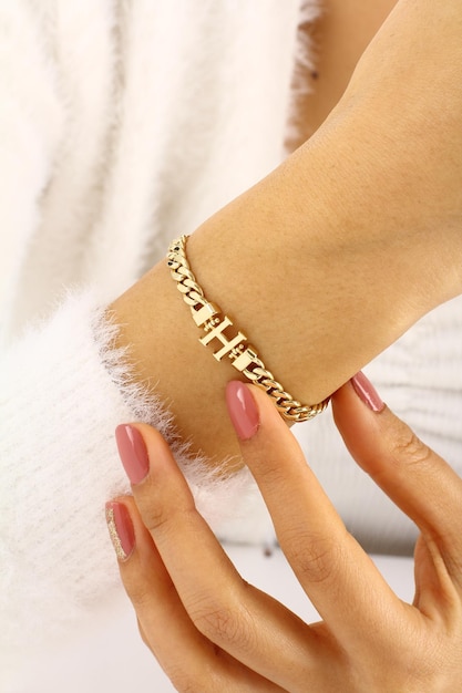 Photo a woman wearing a gold chain bracelet with the word cross on it.