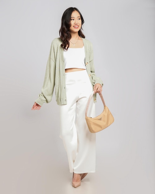 A woman wearing a green cardigan and white pants