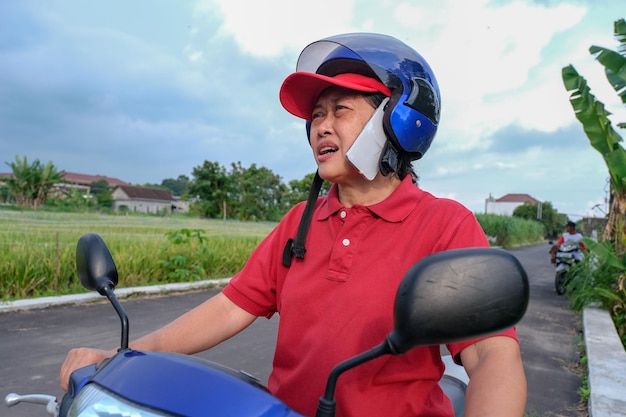 Photo a woman wearing a hat and helmet is talking on her smartphone while riding a motorcycle