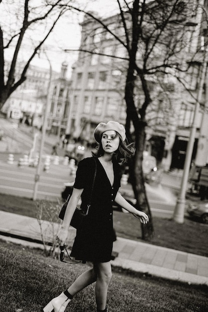 Woman wearing hat looking away while walking against trees