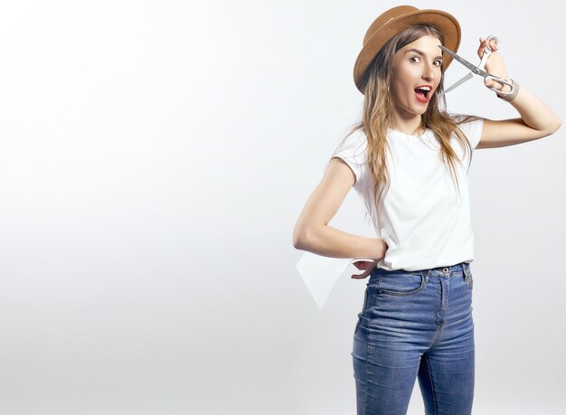 A woman wearing a hat looking through scissors hight quality