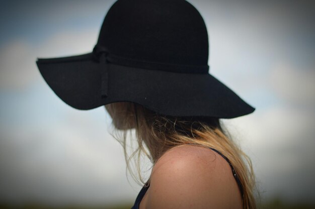 Foto donna con il cappello in piedi contro il cielo