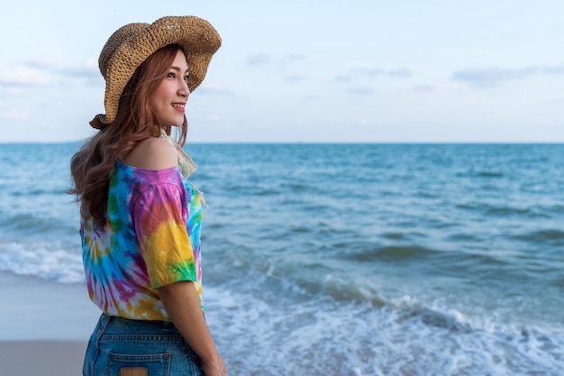 海のビーチの上に帽子立っている女性