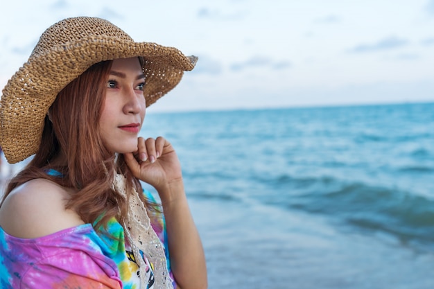 海のビーチの上に帽子立っている女性