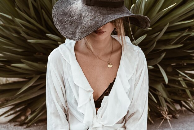 Woman wearing hat while standing against plants