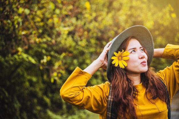 Foto donna che indossa un cappello mentre si trova contro gli alberi