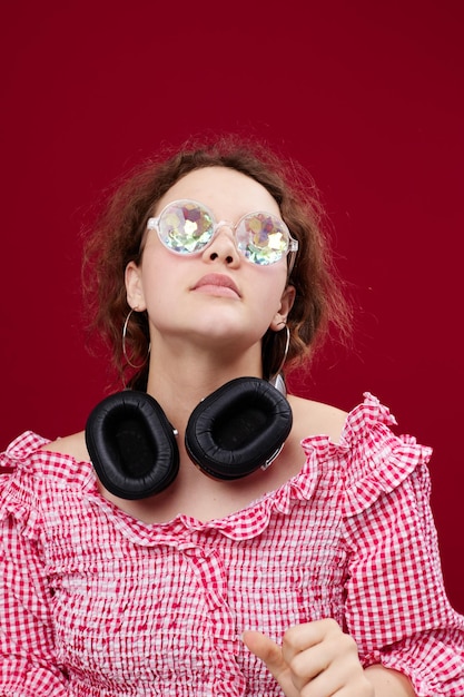 Woman wearing headphones glasses with diamond fashion posing red background