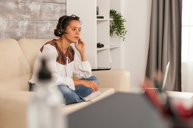 Woman wearing headphones during job video call while working from home.