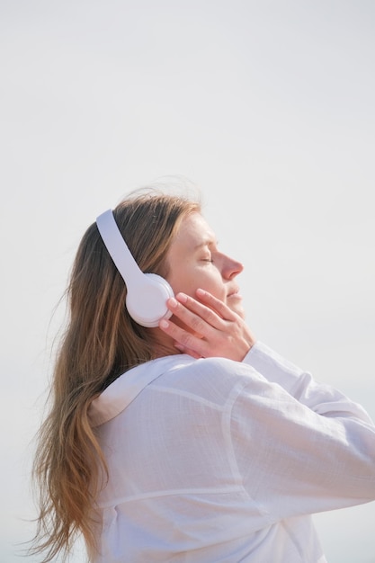 woman wearing headphones listening to music breathing fresh air relaxing on the beach