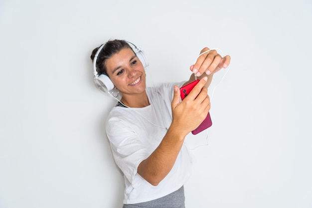 A woman wearing headphones and a red case is looking at her phone.