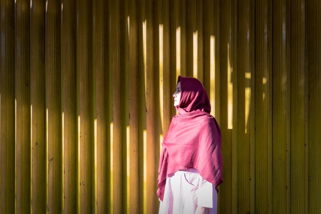 Photo woman wearing headscarf while standing against yellow corrugated iron