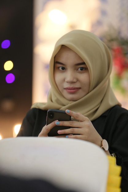 A woman wearing a hijab is looking at her phone.