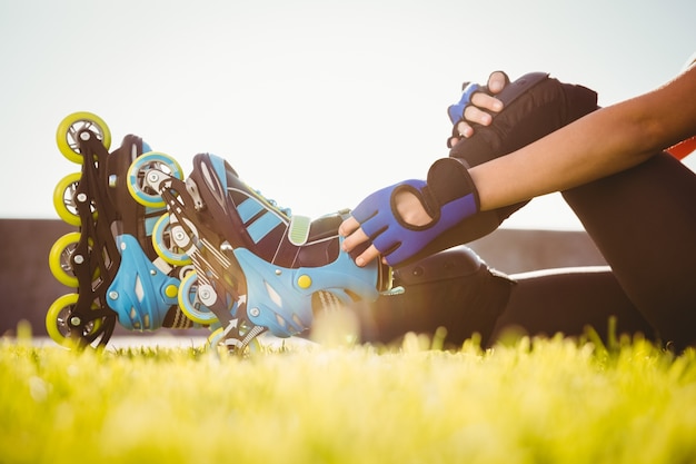 Woman wearing inline skates sitting in grass