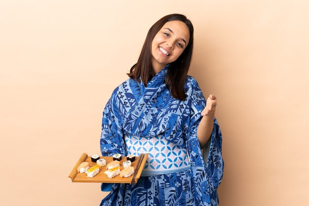 Donna che indossa un kimono e tenendo il sushi su sfondo isolato si stringono la mano per chiudere un buon affare