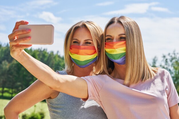 LGBTの旗を身に着けている女性が自分撮りを屋外で撮影します。高品質の写真