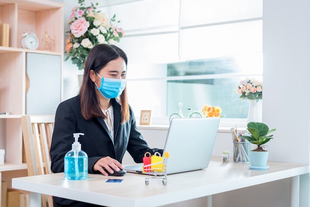 The woman wearing a mask currently working at home and shopping online for self quarantine during the outbreak Corona virus Disease (COVID-19).