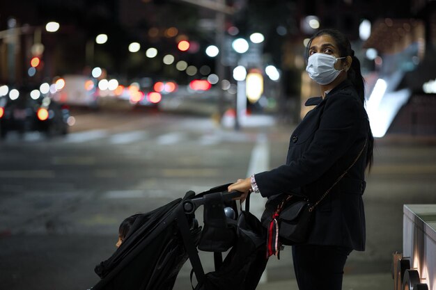 Photo woman wearing mask standing on street with baby