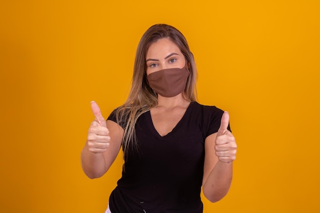 Woman wearing medical face mask from covid19 during pandemic and thumb up