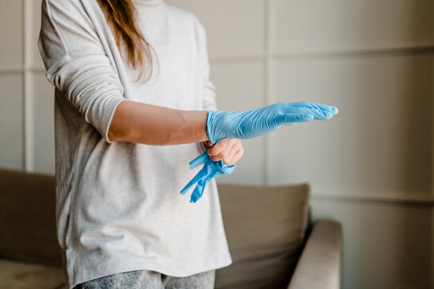 Woman wearing medical gloves at home