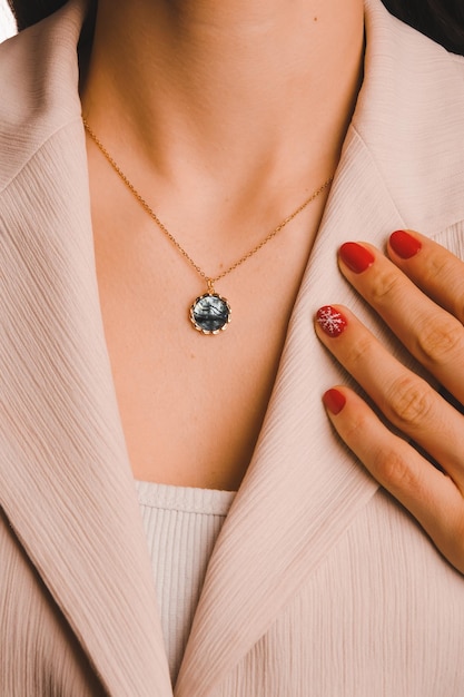 A woman wearing a necklace with a blue stone and a gold pendant.