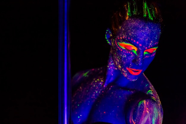 Woman wearing neon clothing by pole against black background