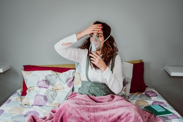 woman wearing oxygen mask while sitting against wall in hospital