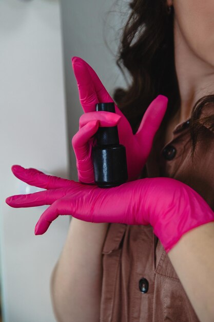 Foto una donna che indossa guanti rosa tiene una bottiglia di liquido.