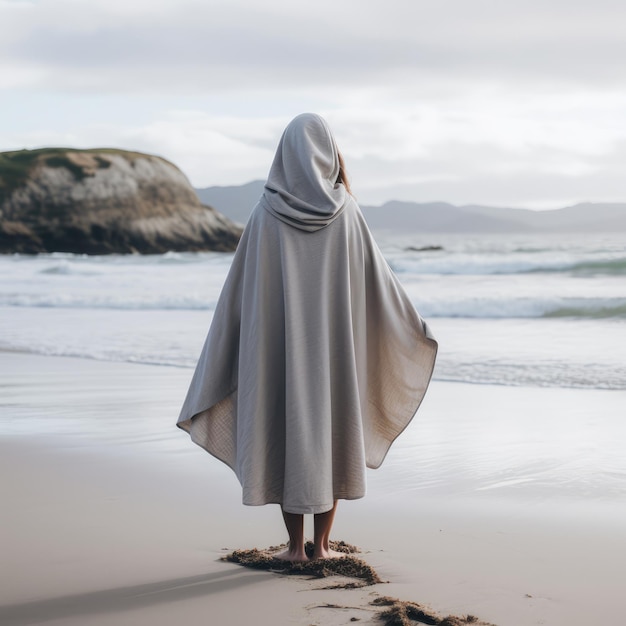 A woman wearing poncho with hoodie on the beach