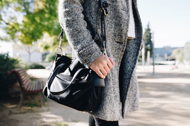 Woman wearing and posing with a coat and purse in autumn collection