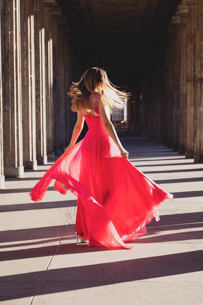 Foto donna con il vestito rosso mentre balla nel corridoio