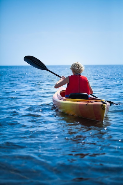 Foto donna che indossa un giubbotto di sicurezza che si dirige verso il mare da sola