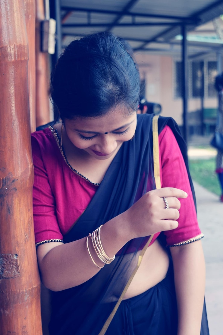 फोटो woman wearing sari while standing by wooden pole