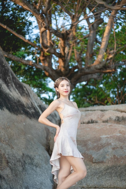 Woman wearing short glitter dress enjoying romantic moment at the beach standing near big rock