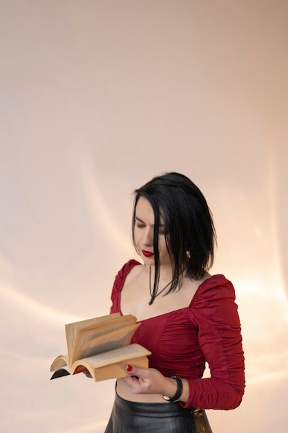 Woman wearing a skirt and red top with a short haircut against a white wall