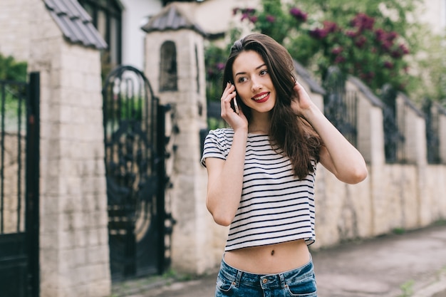 彼女の携帯電話でストライプのTシャツを着ている女性