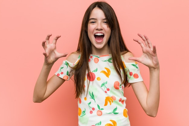 woman wearing a summer clothes against a red wall screaming with rage.