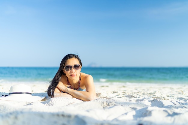 Woman wearing sun glasses enjoying beach relaxing joyful in summer by tropical blue water with copy space