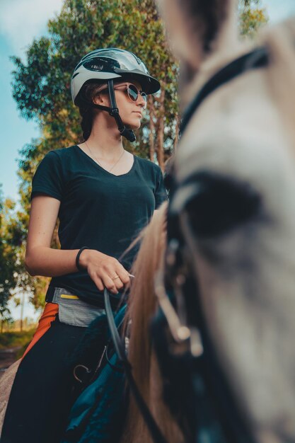 Фото Женщина в солнцезащитных очках и шлеме едет на лошади