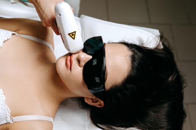 Photo a woman wearing sunglasses holds a white device with a triangle on it