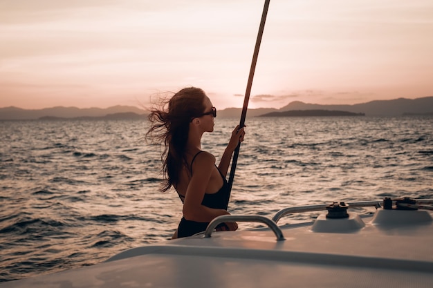 woman wearing swimsuit and glasses posing on her yacht