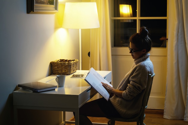 Woman wearing a warm woolen sweater is reading book