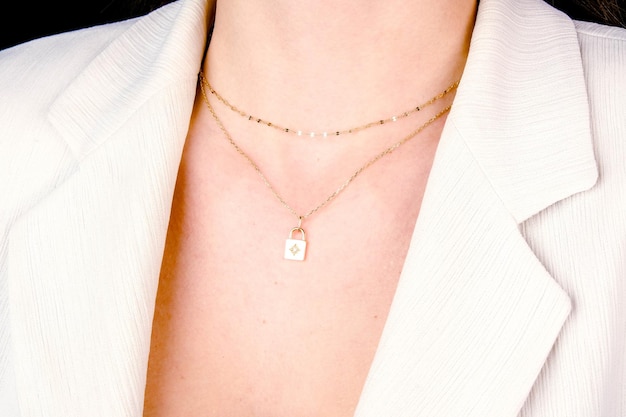 a woman wearing a white jacket with a diamond necklace on it
