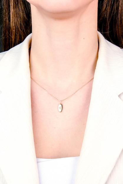 Photo a woman wearing a white jacket with a pendant on it