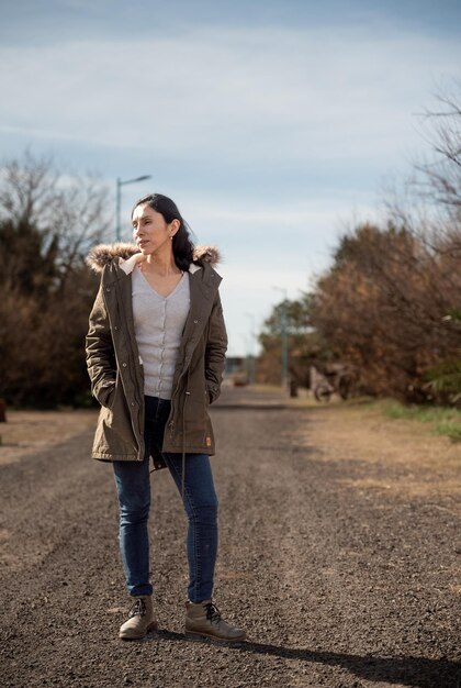 Foto una donna che indossa una camicia bianca e jeans si trova in una strada di ghiaia.